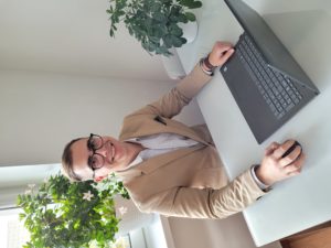 Mateusz Grabarczyk siedzący przy stole za komputerem w otoczeniu roślin doniczkowych