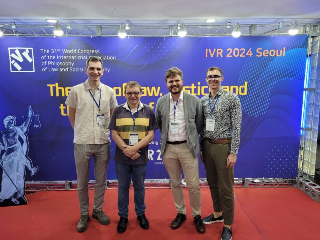 Photo of department's members at the IVR congress in Seoul in the background of the conference poster. From left: mgr W. Rzepiński, prof. dr hab. M. Smolak, dr M. Krotoszyński i mgr M. Grabarczyk